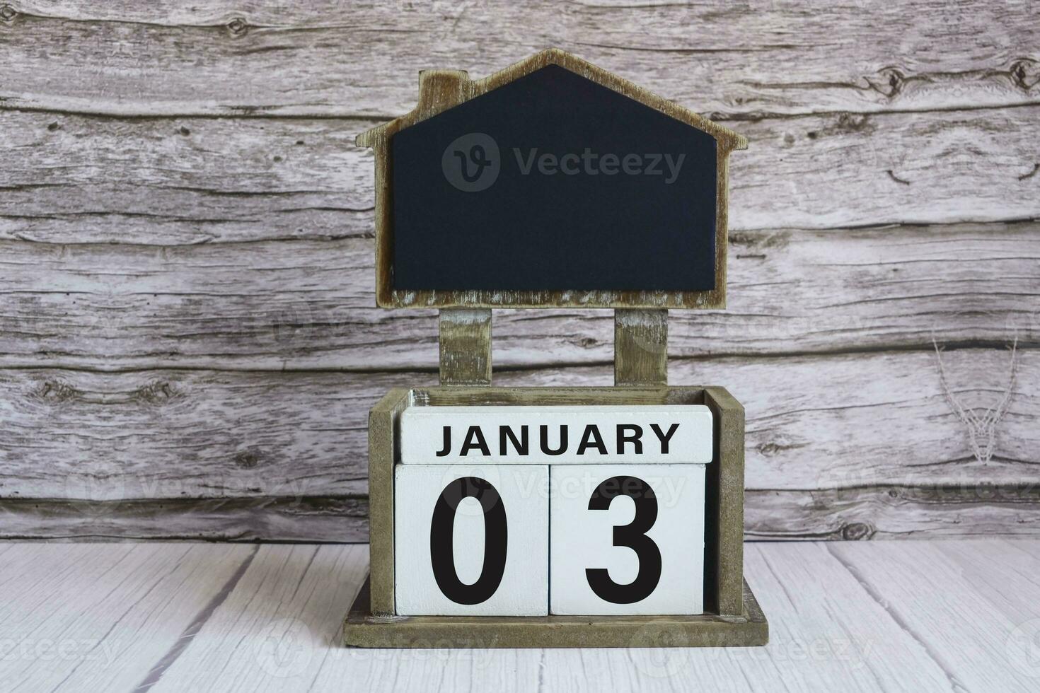 Chalkboard with January 03 date on white cube block on wooden table. photo