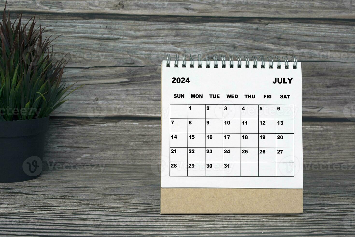 White July 2024 calendar on wooden desk. 2024 New Year Concept photo