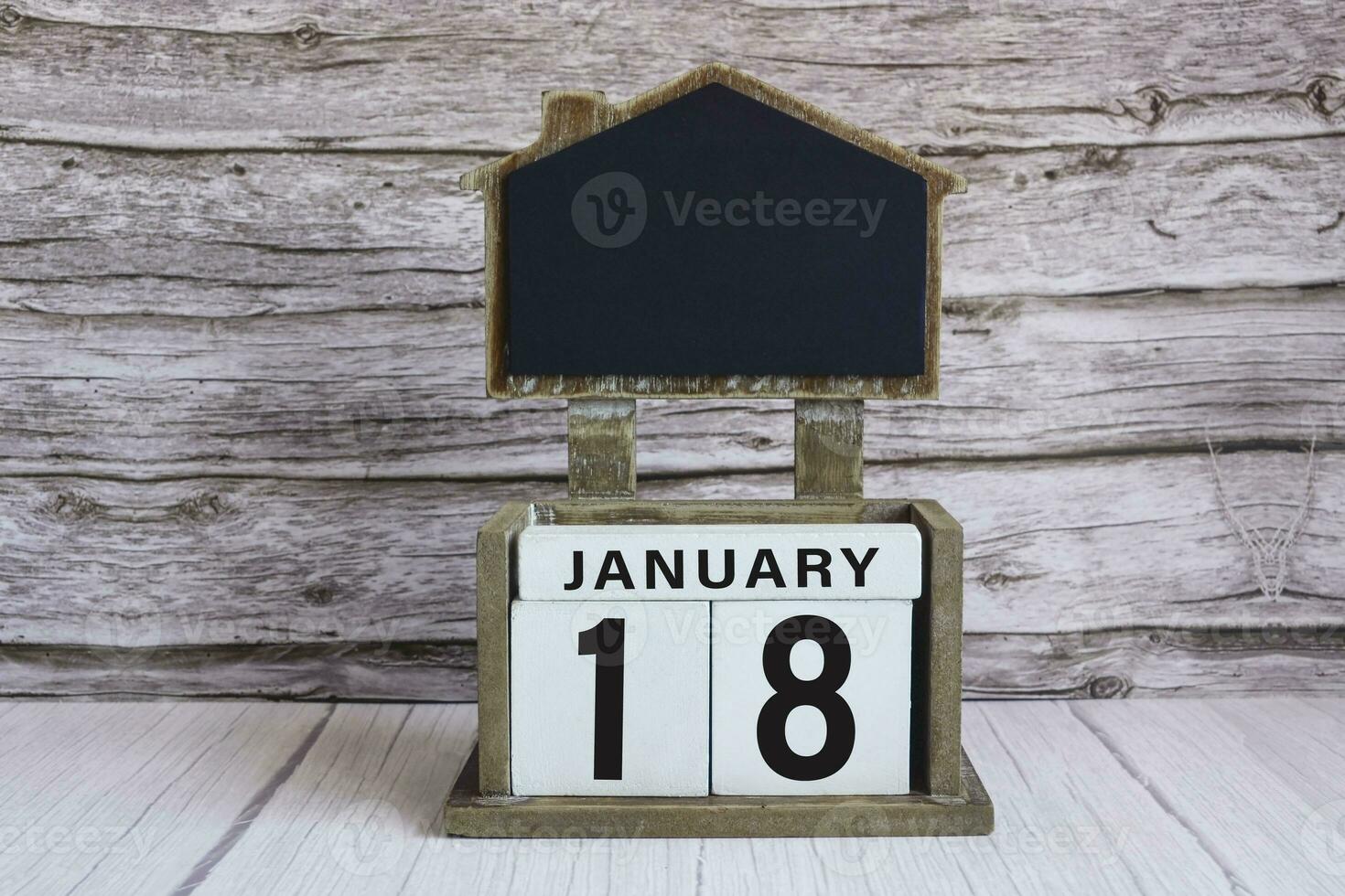 Chalkboard with January 18 date on white cube block on wooden table. photo