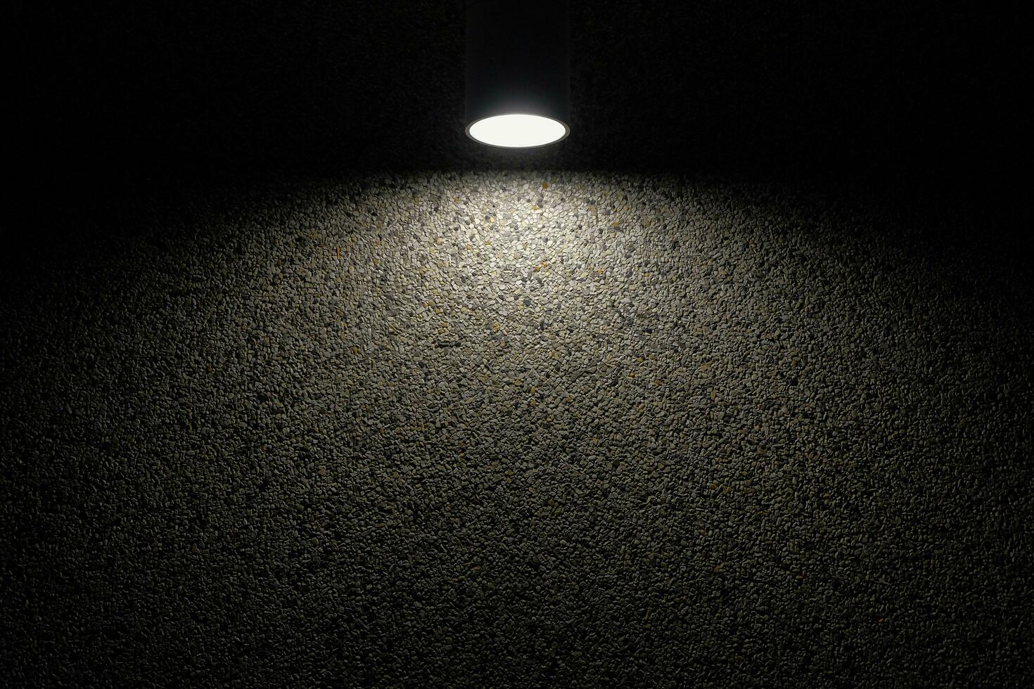 Exterior illuminated wall light modern Nordic style. Balcony LED wall light illuminated on textured concrete wall at night. Black glowing lamp hanging on the wall. Selective focus and copy space. photo