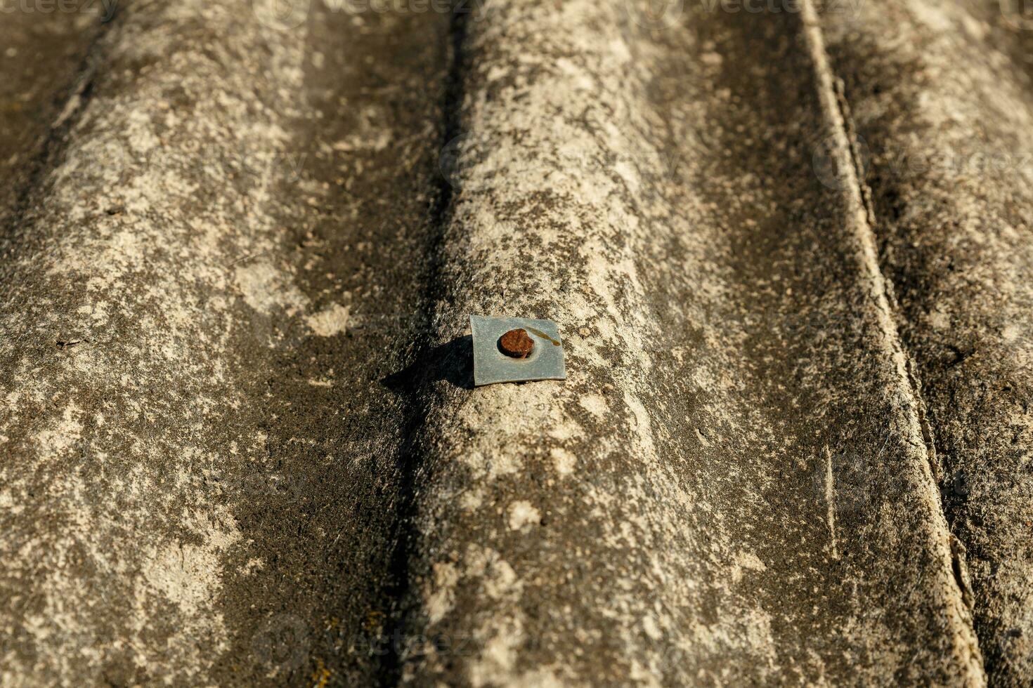 A rusty nail with a metal gasket on a slate roof. photo