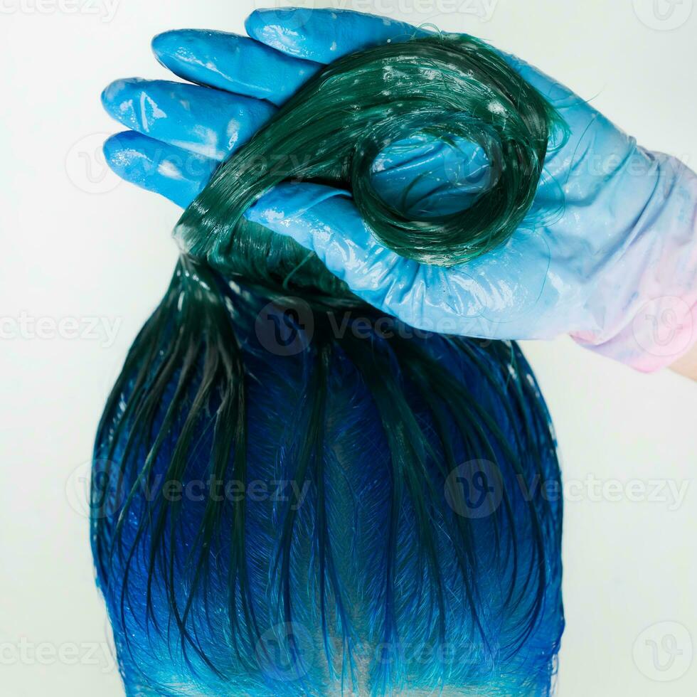 Washing of woman hair with shampoo in sink with special shower. Top view of hairstylist in gloves washes customer long hair sapphire color photo