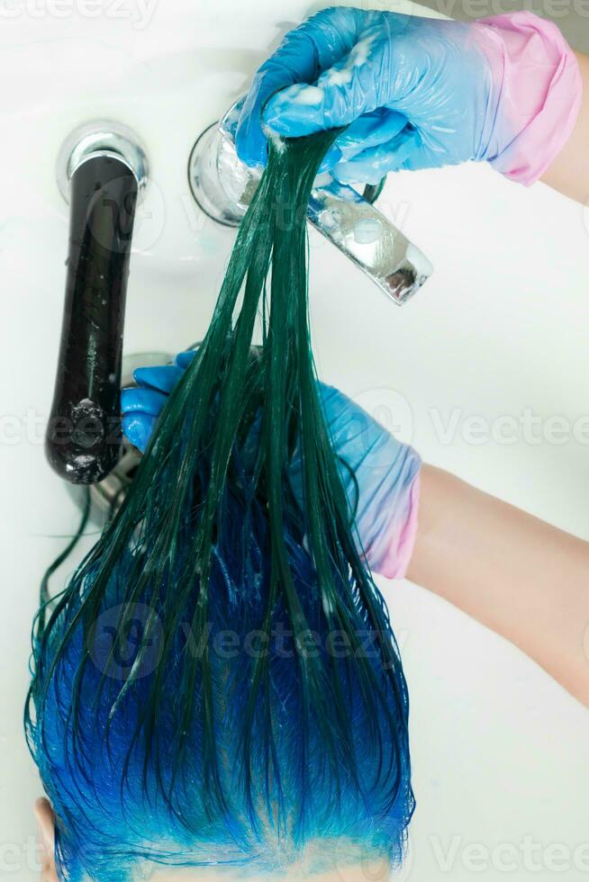 High-angle shot of hairdresser shampooing client's head with long hair sapphire color after dyeing hair process photo