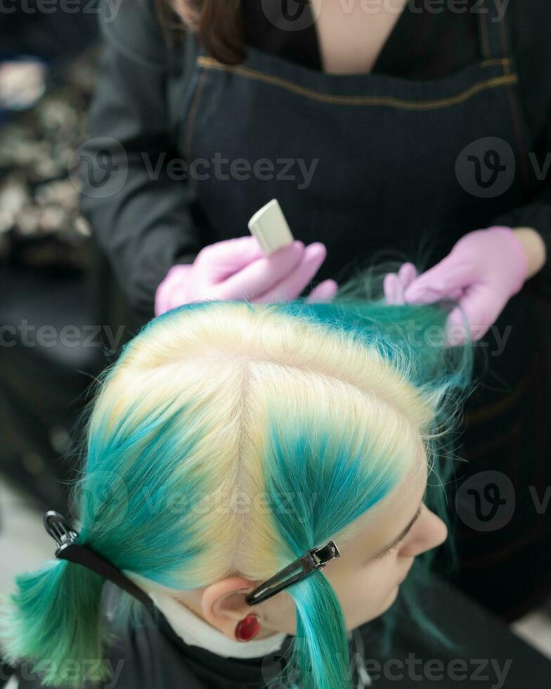 parte superior ver de cabeza de joven mujer con verde pelo y blanqueado pelo raíces en profesional belleza salón foto