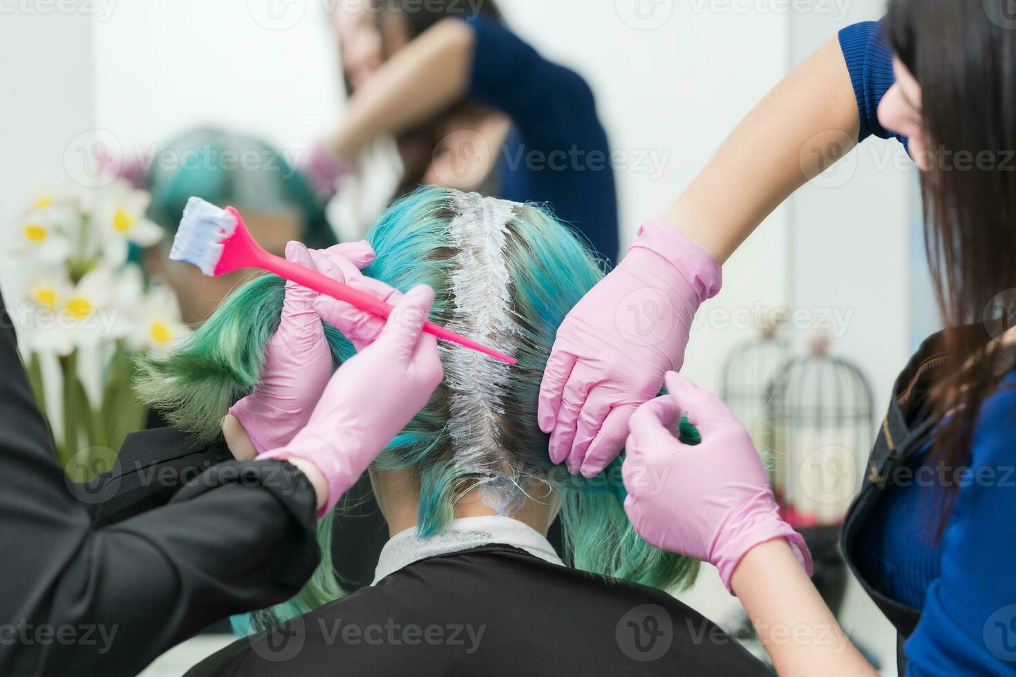 Process of hair dyeing in beauty salon. Two hairdressers applying paint to hair during bleaching hair roots photo