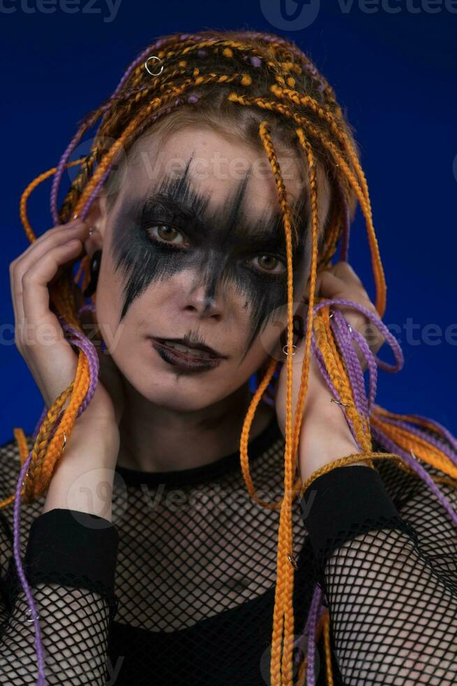 Dramatic portrait of young female with horror black stage makeup painted on  face and orange color dreadlocks hairstyle. Studio shot on blue background  Stock Photo - Alamy