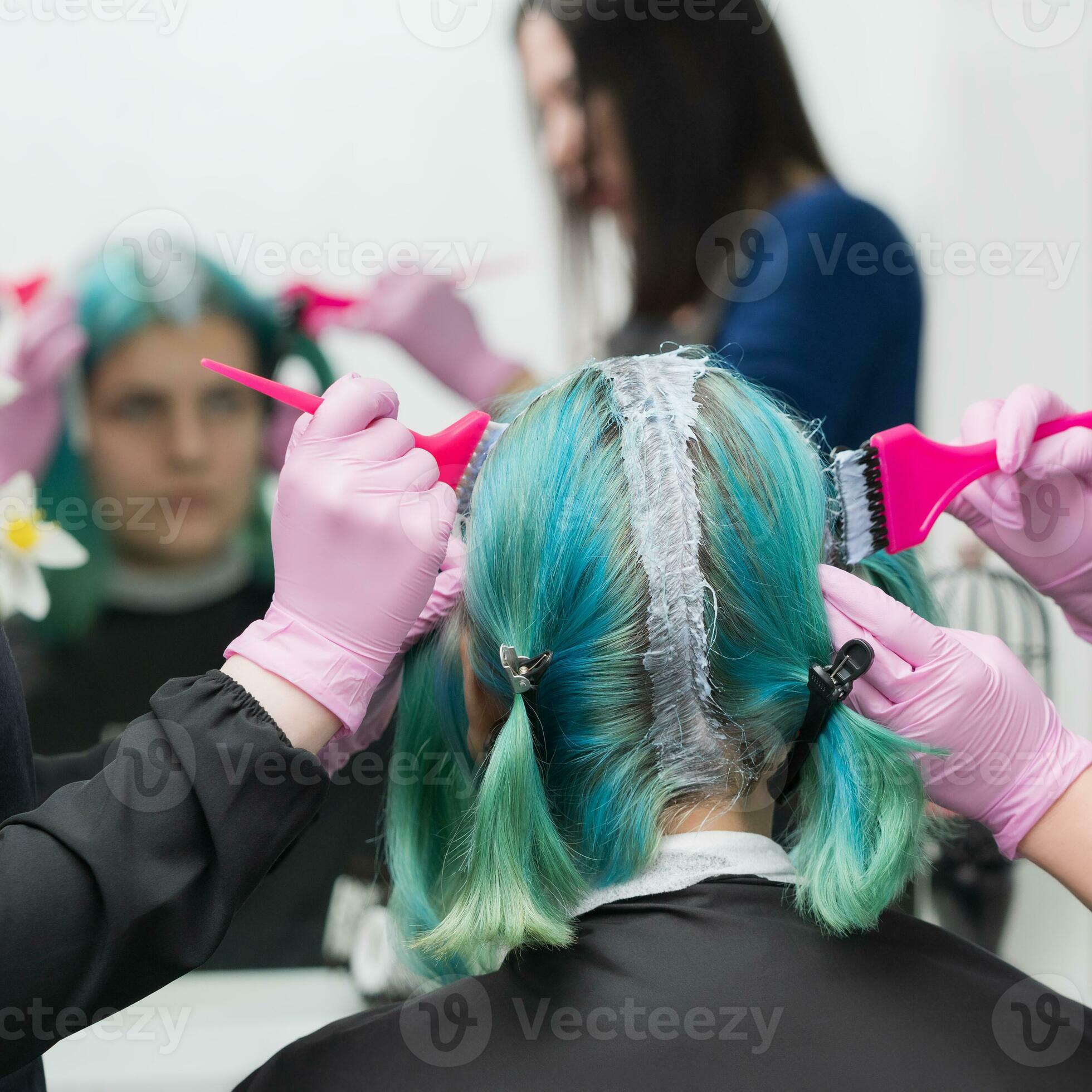 Process of hair dyeing in beauty salon. Two hairdressers applying paint