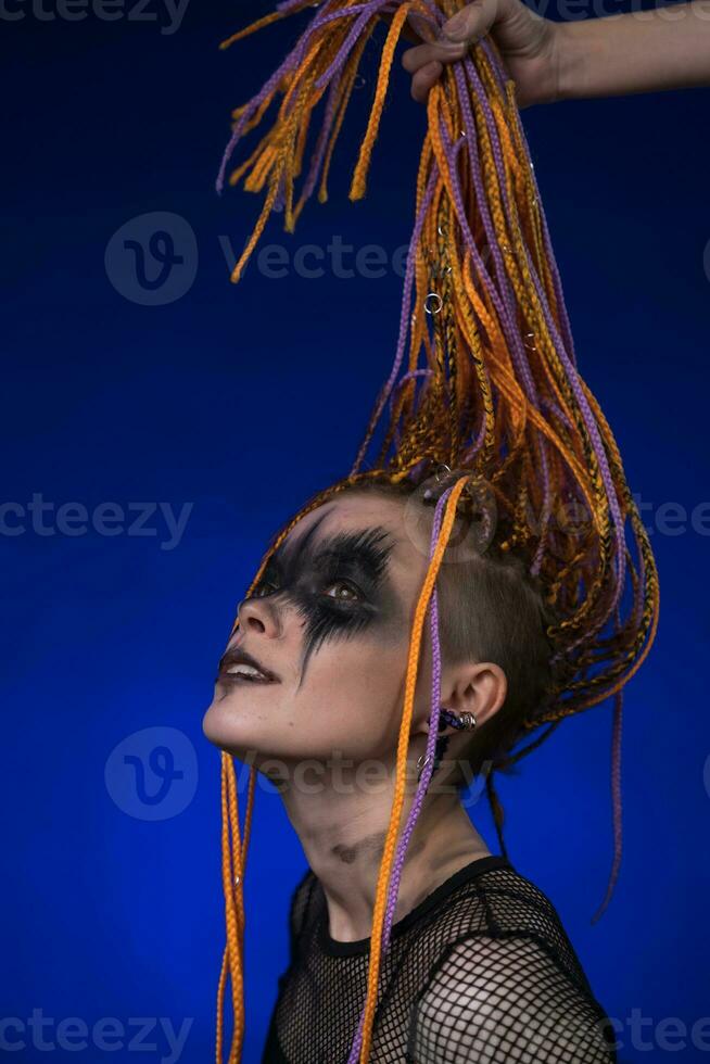 joven mujer con naranja color trenzas peinado y horror negro etapa hacer arriba pintado en cara foto