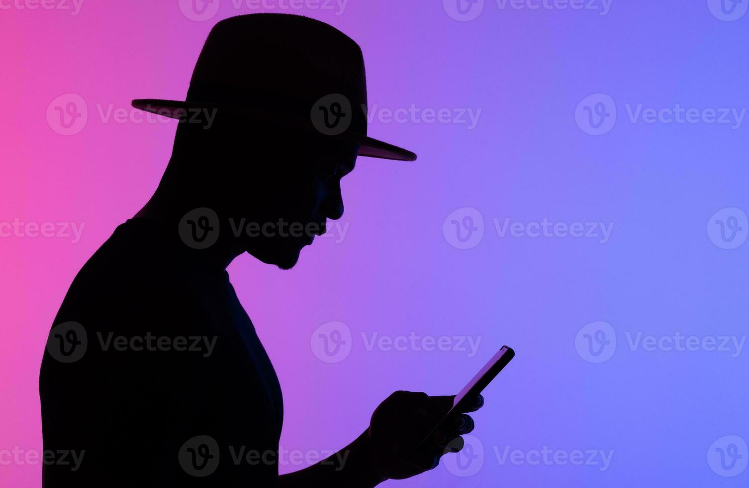 Confident african man silhouette using mobile phone while standing to neon background copy space and empty space for text photo