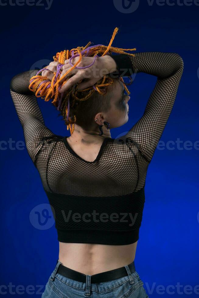 Rear view of young woman with colored braids hairdo and horror black stage make-up painted on face photo