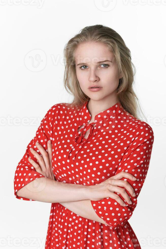 Portrait of serious young blonde woman has her arms crossed over chest and looking at camera photo
