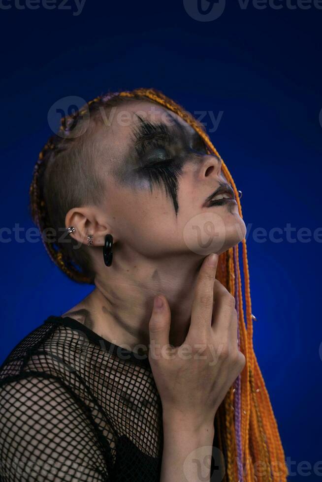 Dramatic portrait of young female with horror black stage makeup painted on  face and orange color dreadlocks hairstyle. Studio shot on blue background  Stock Photo - Alamy