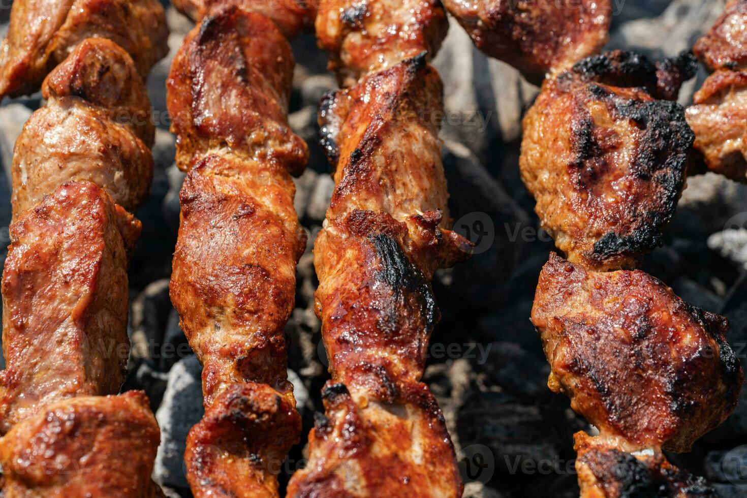 Pork shish kebab cooking on skewers on charcoal grill with fire smoke photo