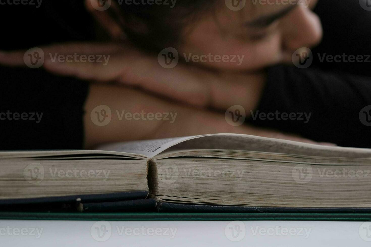 Tired young woman lying on a book after hard work. photo