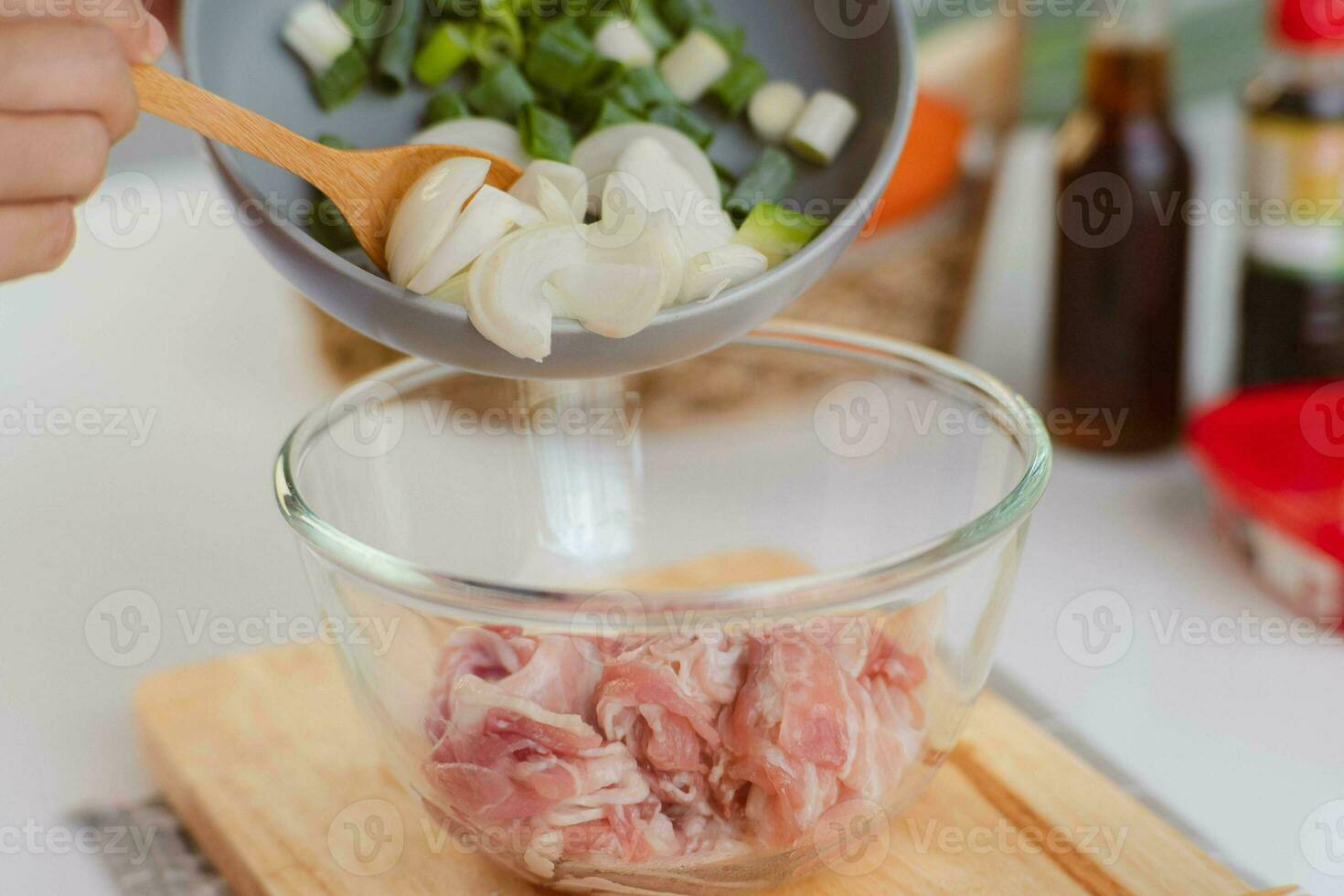 Step-by-step procedures to marinate pork for easy Korean cooking, add chopped onions and Japanese bunching onion, sesame oil, soy sauce, Korean gochujang and mix well. Korean homemade food for lunch photo