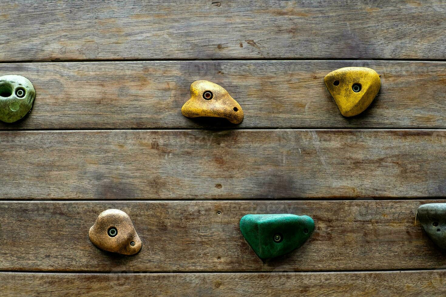 Wooden wall playground with rock climbing simulator design at outdoor playground in park. Wooden planks playground with colorful stone cliff climbing model in the public garden. photo