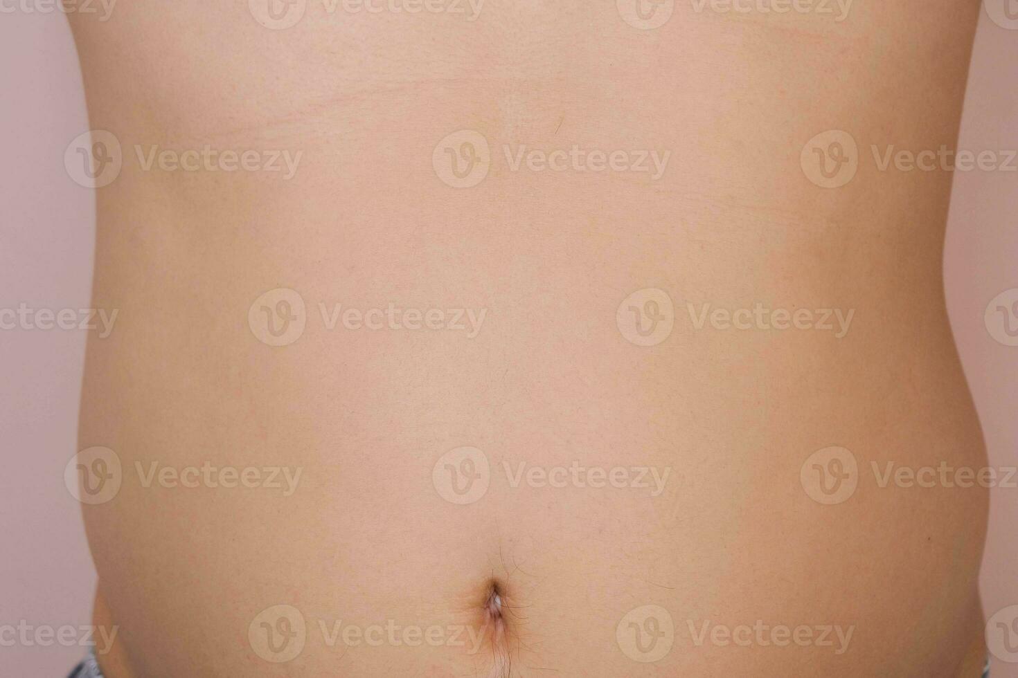 Man showing his fat belly isolated on pink background. Overweight young man with big belly photo
