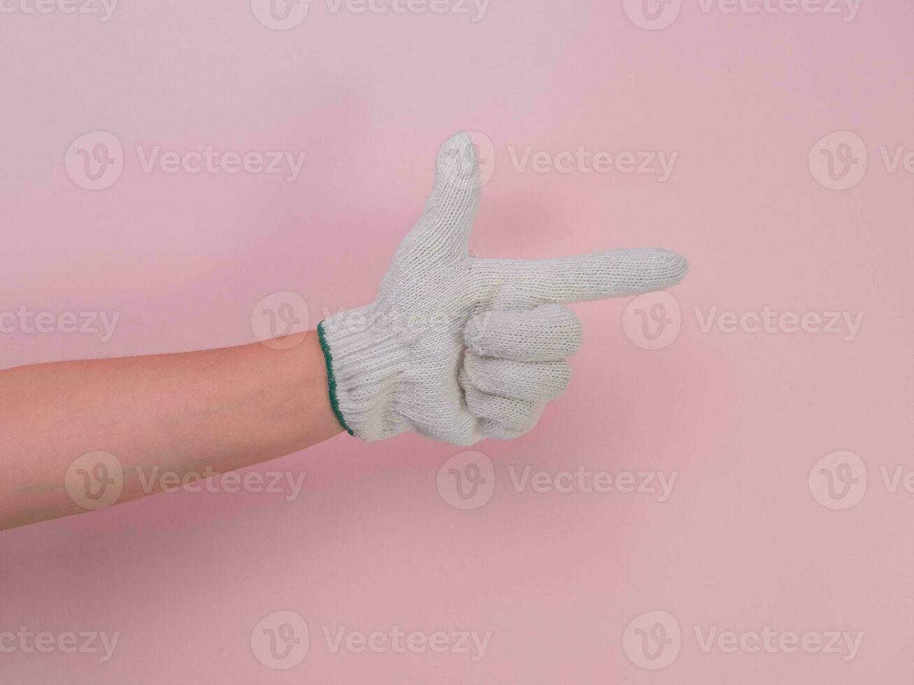 Hands in white knitted gloves isolated on pink background. Female hand pointing with a cotton glove. photo