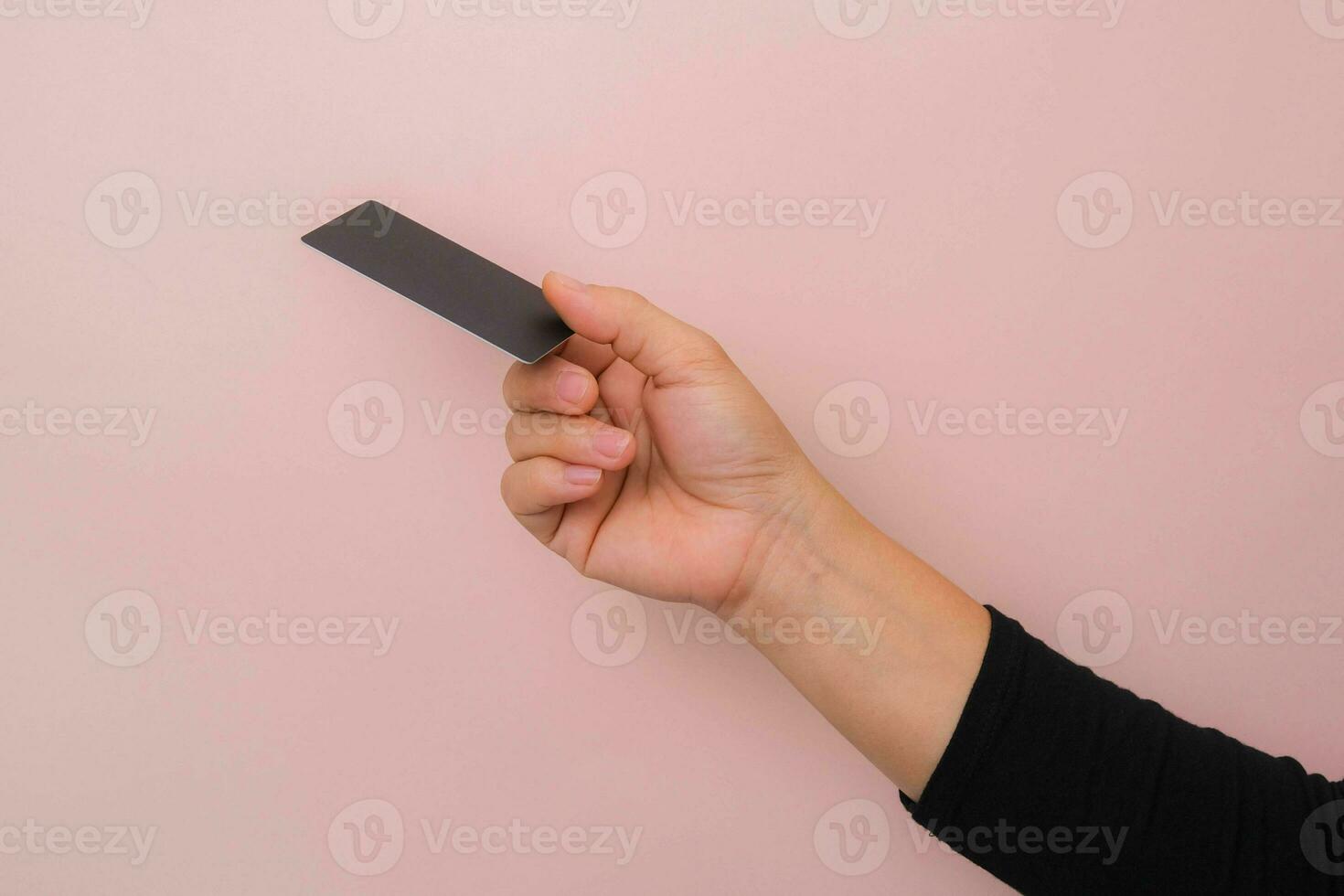 Close up of woman's hand holding blank black card isolated on pink background. photo