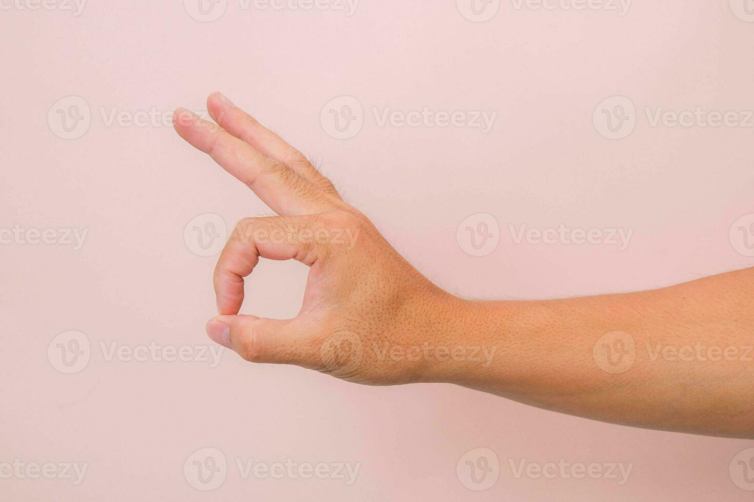 Male hand showing okay gesture isolated on pink background. photo