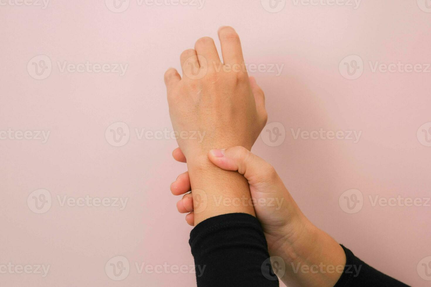 Close-up of woman's hand holding her painful wrist from Arthritis or Carpal Tunnel Syndrome  isolated on pink background. Health care concept. photo