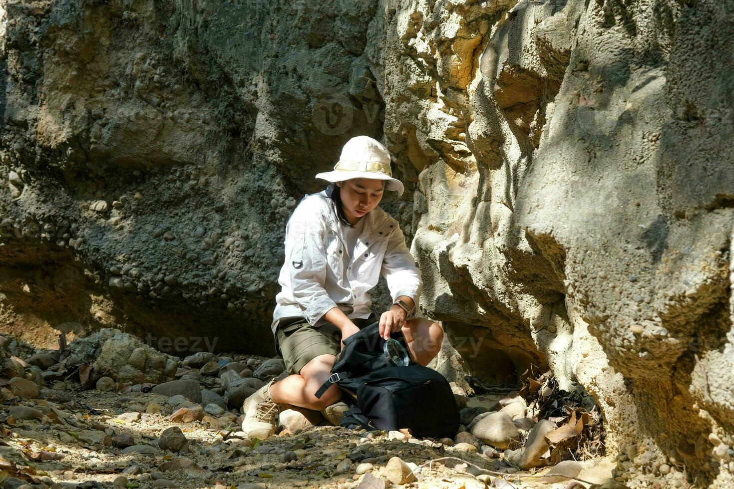 Female geologist using a magnifying glass examines nature, analyzing rocks or pebbles. Researchers collect samples of biological materials. Environmental and ecology research. photo