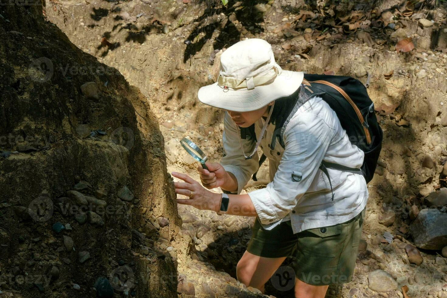 Female geologist using a magnifying glass examines nature, analyzing rocks or pebbles. Researchers collect samples of biological materials. Environmental and ecology research. photo
