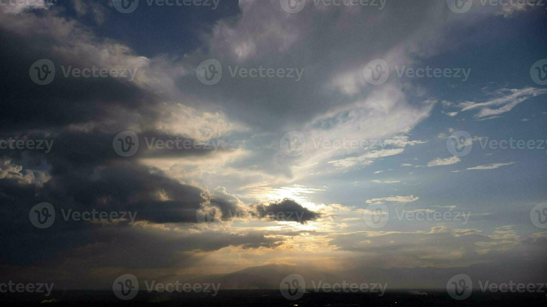 Time lapse of the beautiful scenery of the sunset sky with the golden rays of the sun against the background of the silhouette of the mountain landscape. Natural landscape background. photo