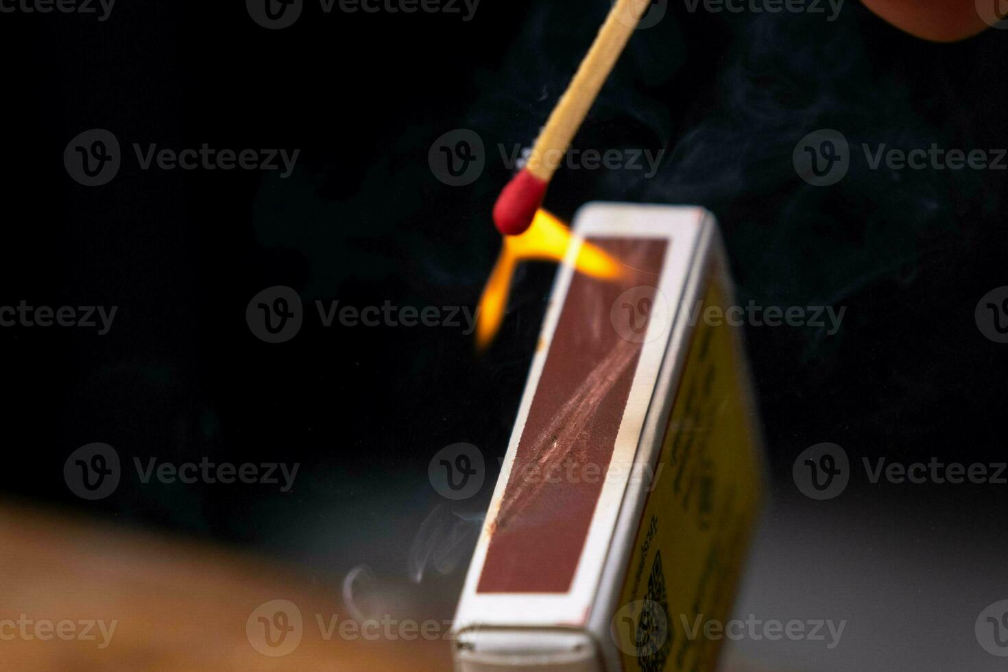 Matchstick fires on matchbox in slow motion close-up. The match was being lit, a blazing fire. Shot of igniting match against black Background. photo