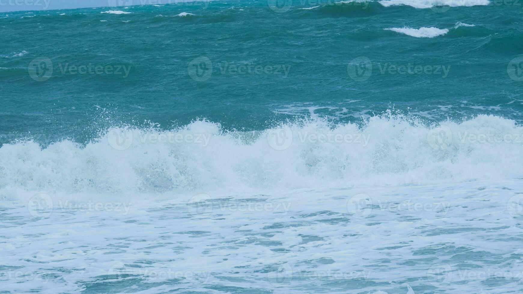 View of sea waves on the beach of tropical seas in Thailand. Strong sea waves crash to shore in the rainy season. Beautiful sea waves with foam of blue and turquoise color. photo