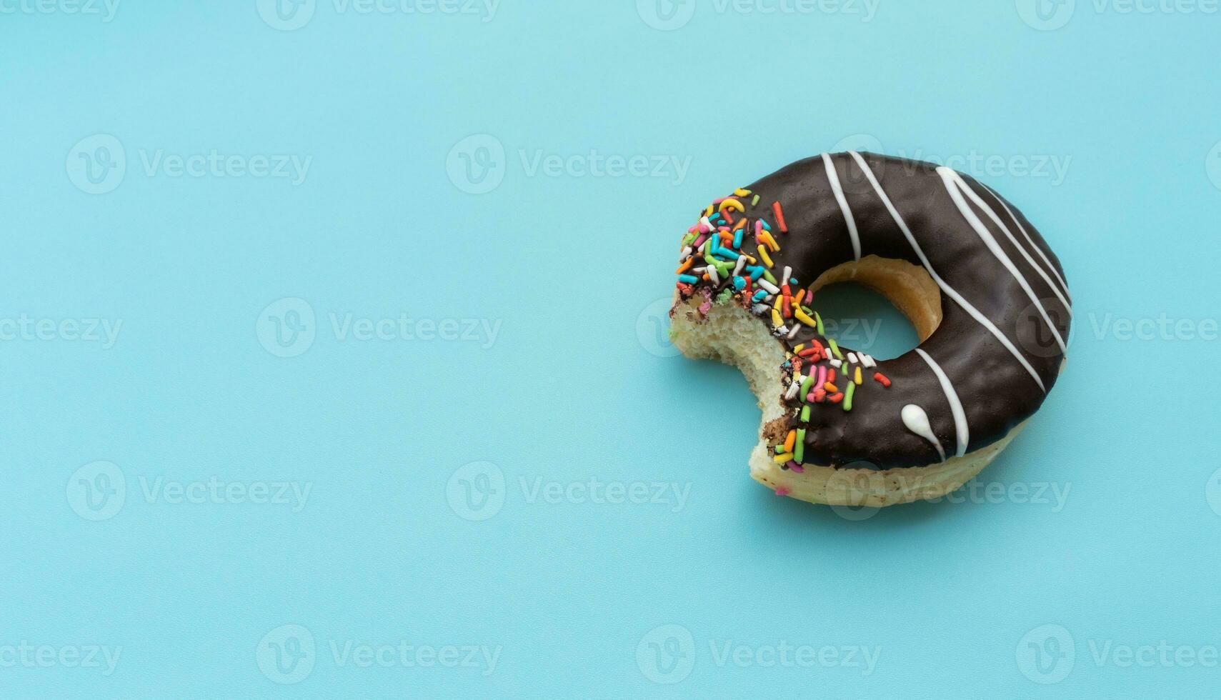 Messy chocolate doughnut isolated on blue background, after some edits. photo