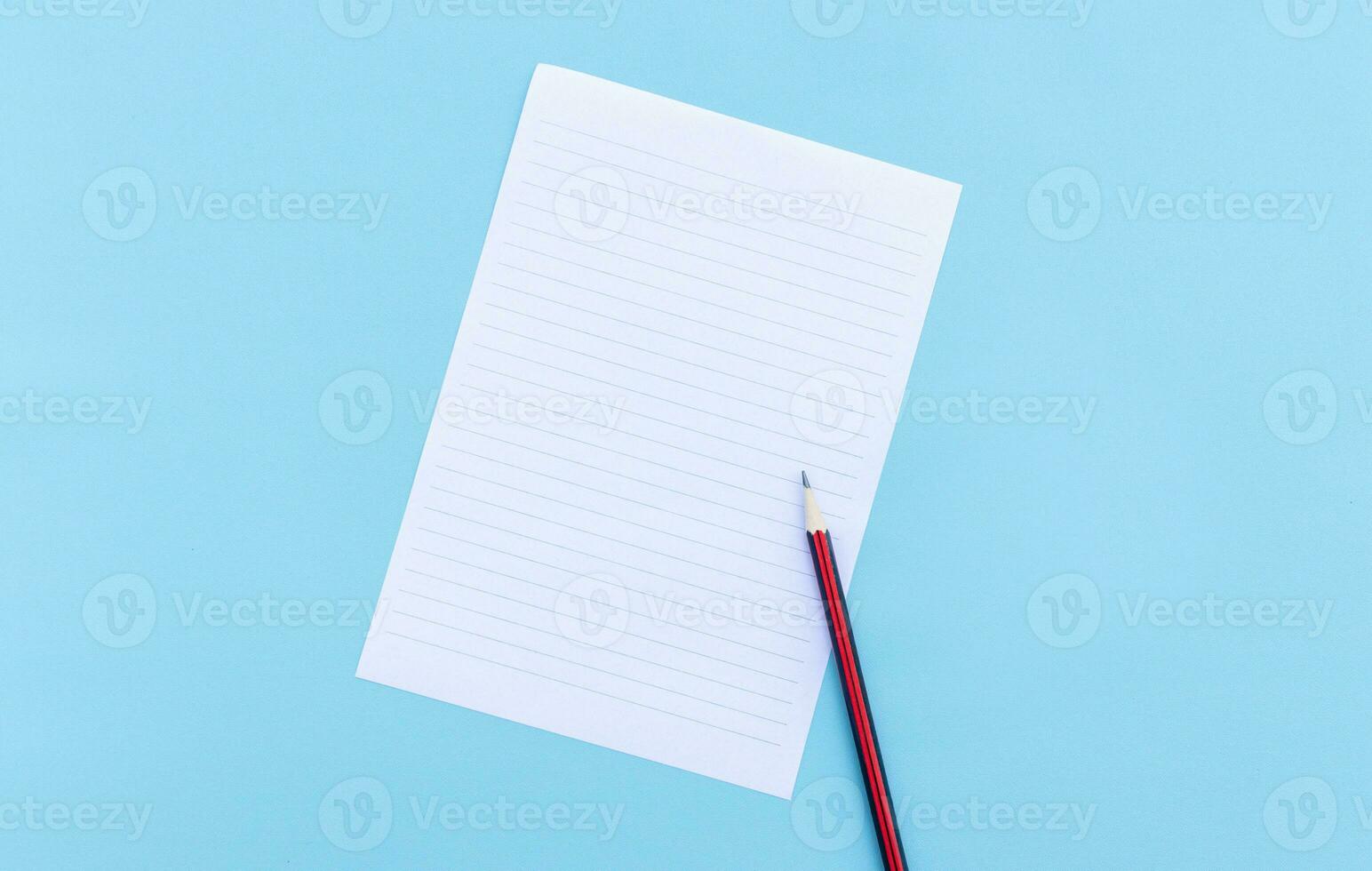 Blank white paper and pencil isolated on blue background. After some edits. photo