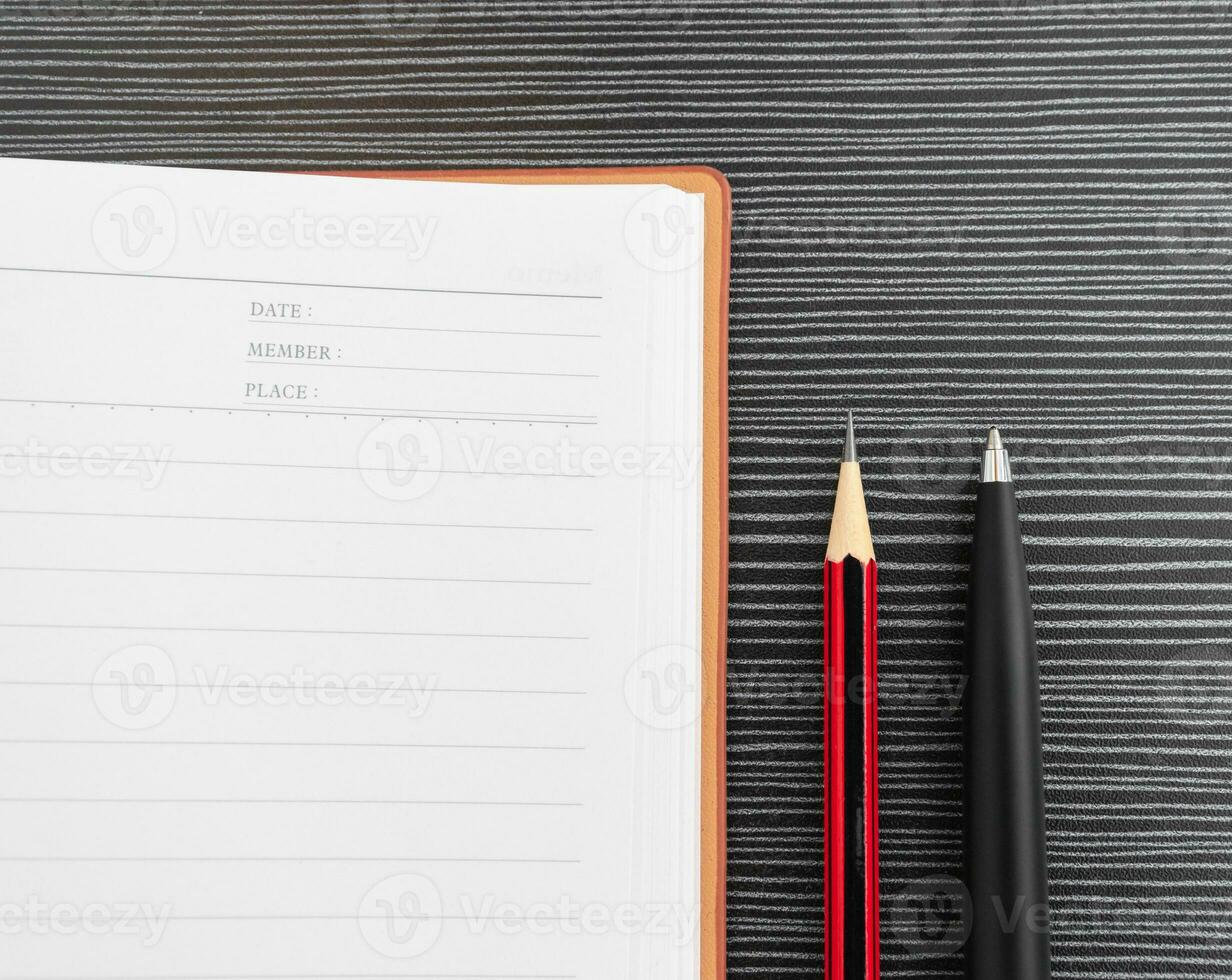 un bolígrafo, lápiz y libro metido en texturizado mesa. después algunos ediciones foto