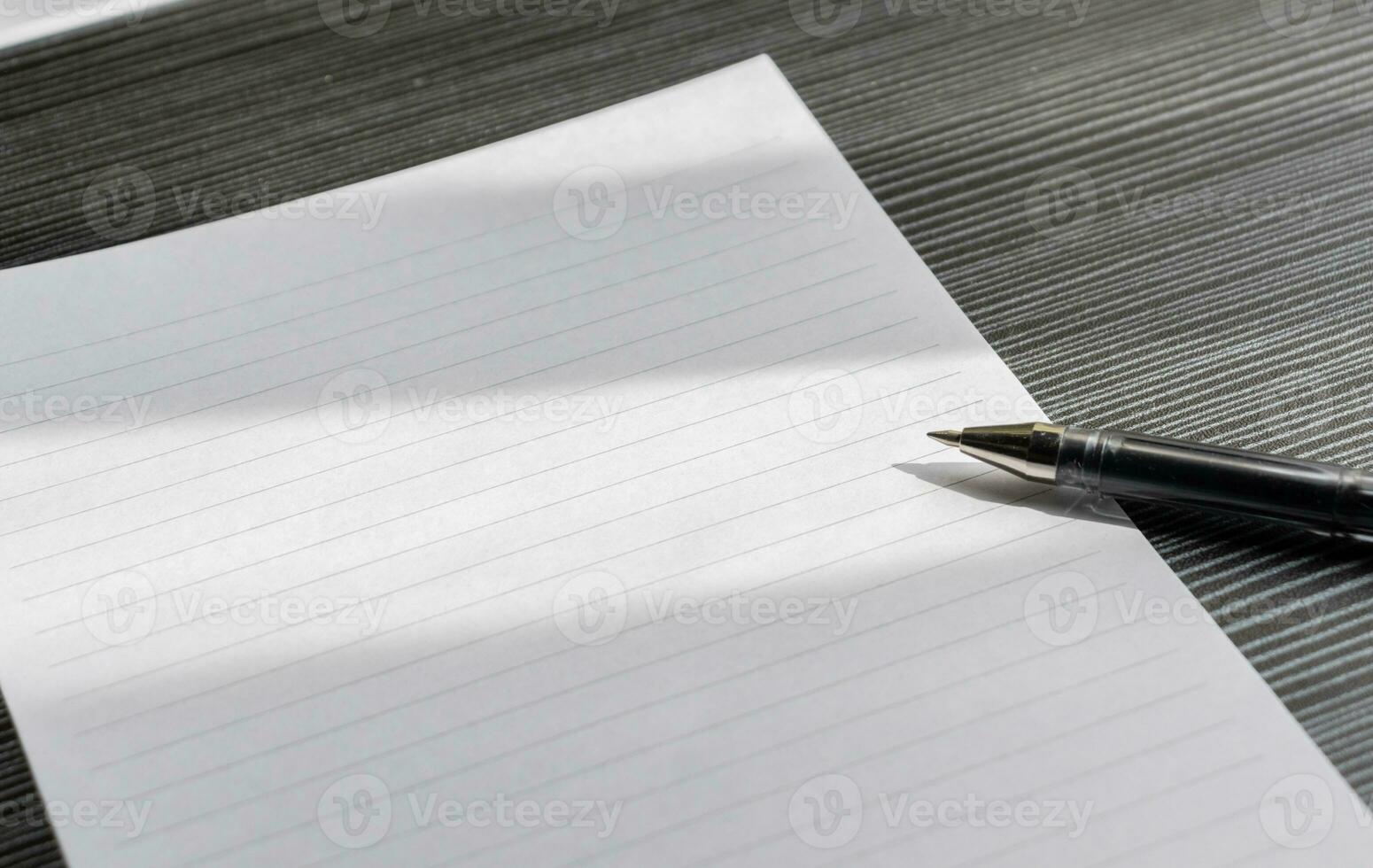 Broken pencil and a blank paper on a wooden textured table with partial shadows, after some edits. photo