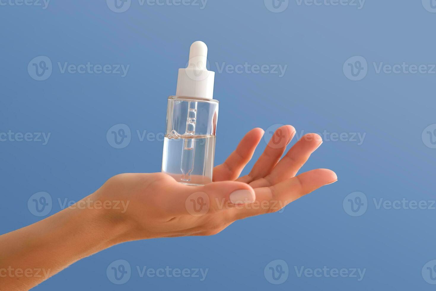 Serum with a pipette in female hands on a blue background. photo