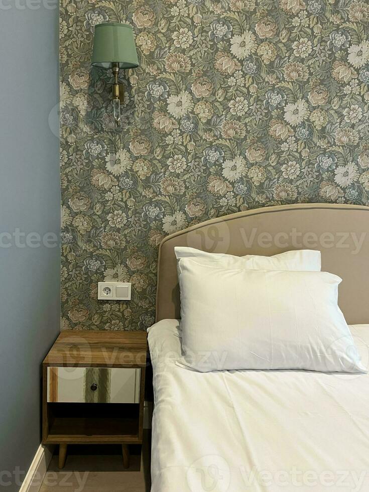 A fragment of a bedroom with a modern cozy interior design of a house or hotel. Soft pillow and blanket, stylish comfortable furniture. photo