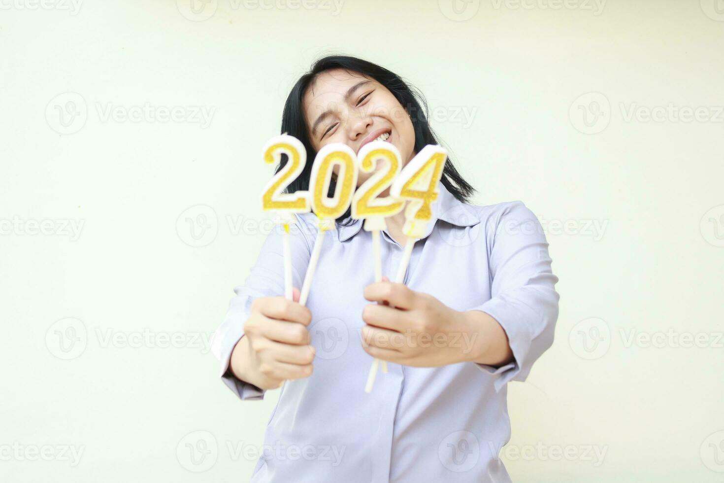 contento asiático joven negocio mujer vistiendo gris formal traje sonriente a cámara demostración 2024 figura velas a anunciar nuevo años víspera, aislado en blanco. mirando a cámara foto