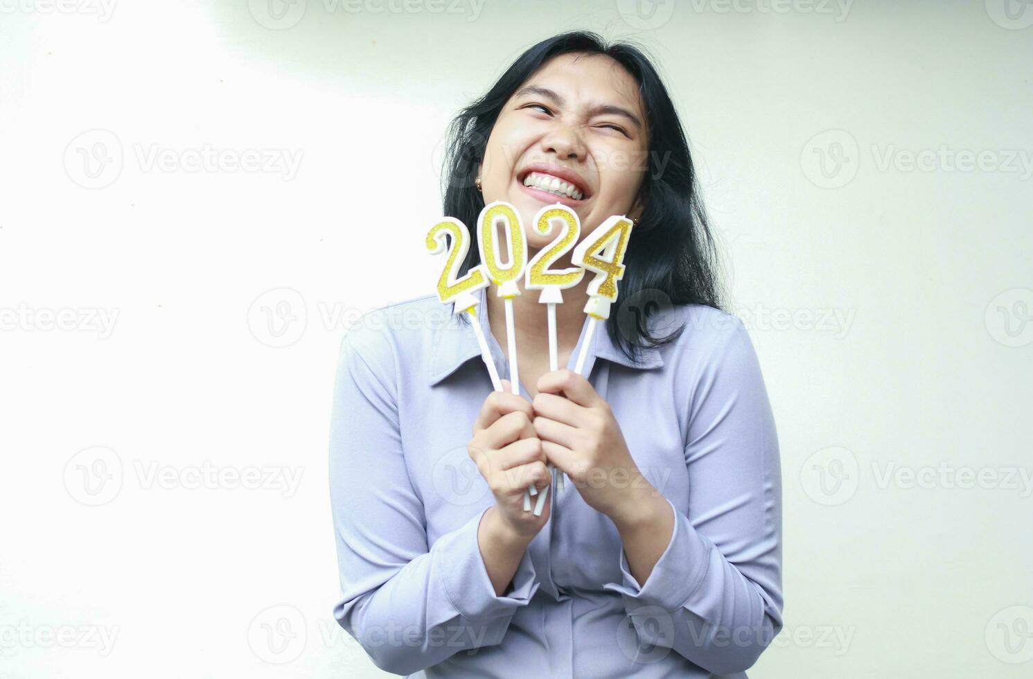 alegre asiático joven negocio mujer riendo con con dientes sonrisa y mirando aparte, levantamiento 2024 figura velas participación en mano, aislado, hembra compañero de trabajo vestir gris formal traje celebrando nuevo año víspera foto