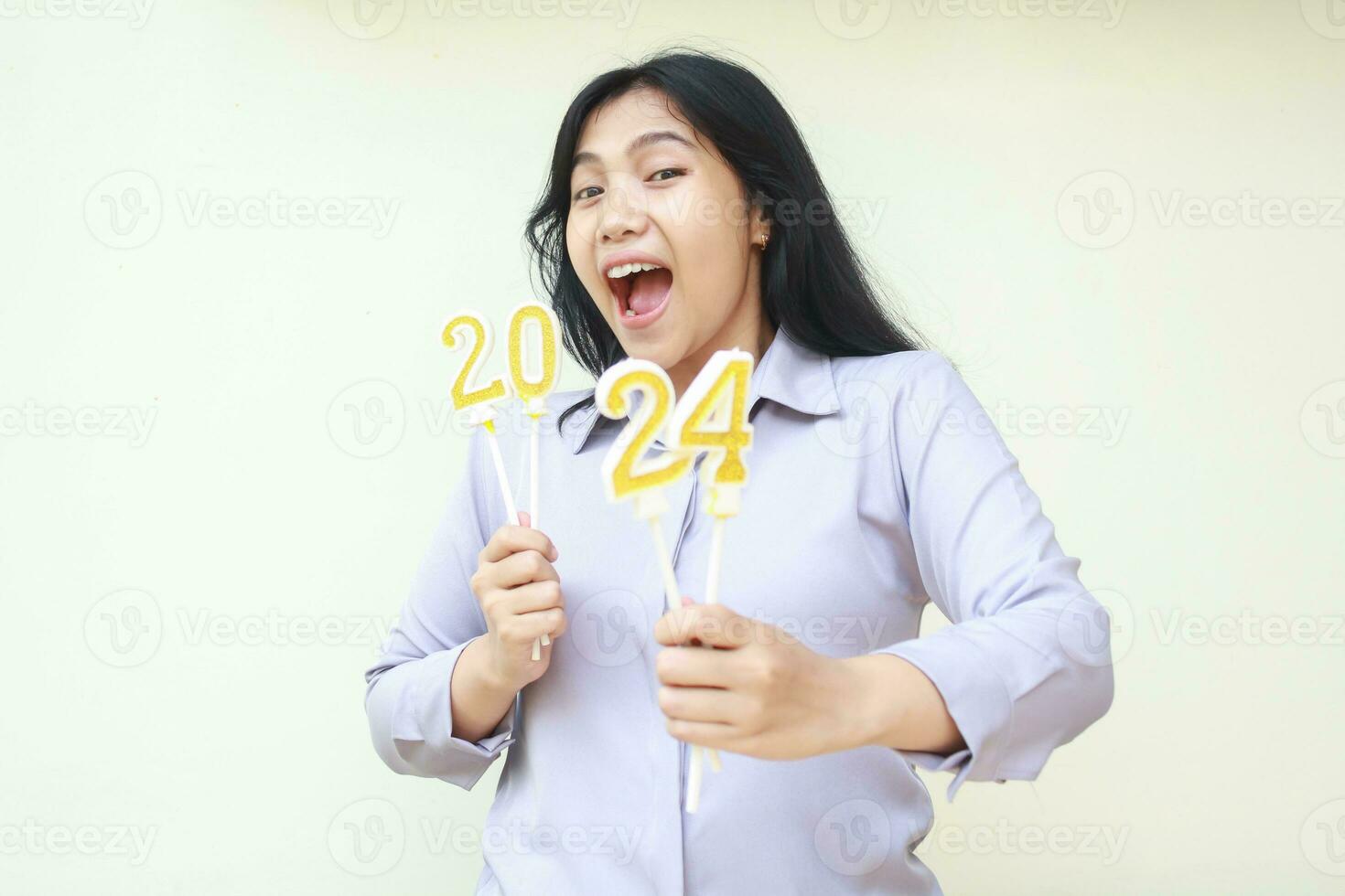 surprised asian young business woman screaming to camera with open mouth wearing grey formal suit, female coworkers holding 2024 number candle, new years eve concept, isolated photo