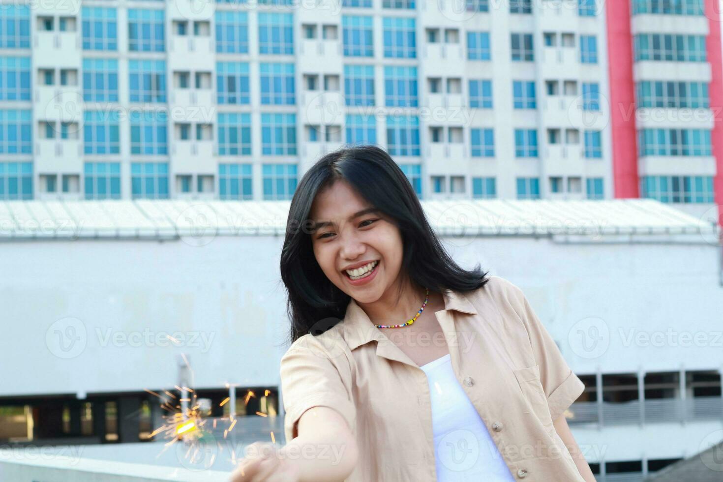 happy asian young woman holding sparklers celebrate new year eve in outdoor roof top with city building background photo