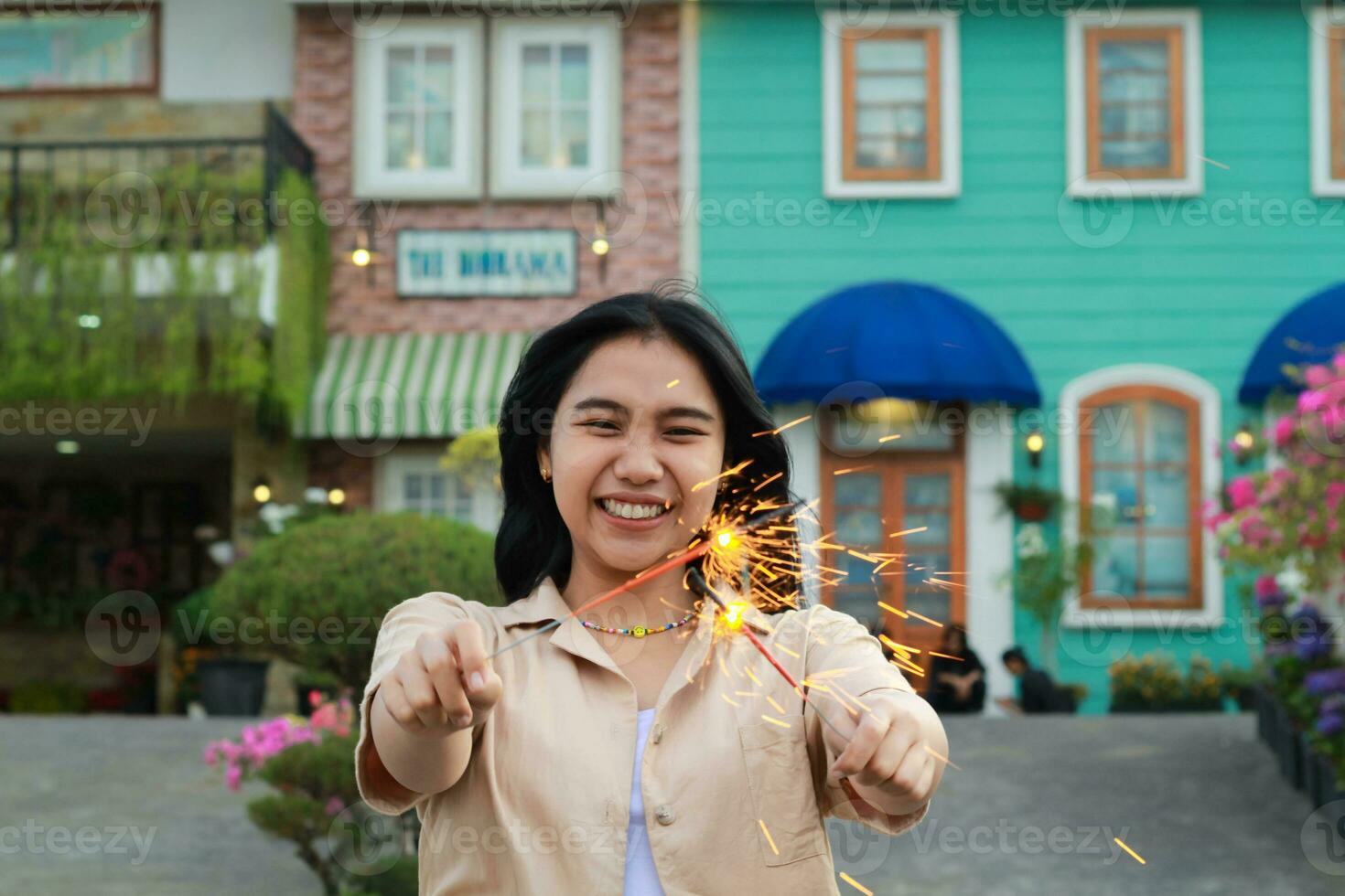 happy young asian woman holding sparkler celebrating new year eve in vintage house yard, outdoor garden photo