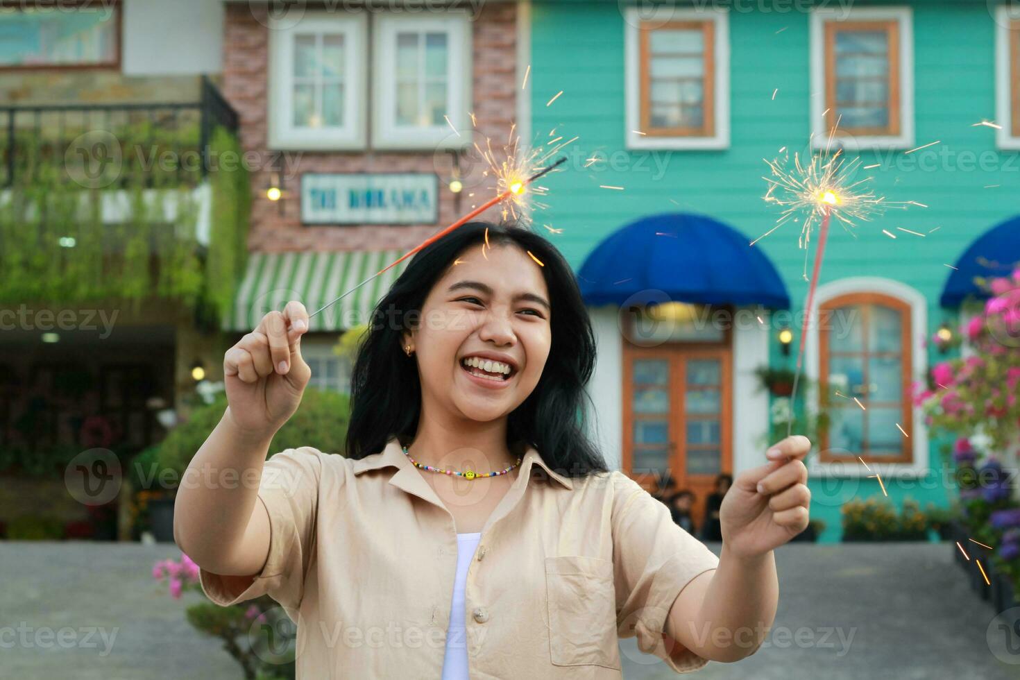 happy young asian woman holding sparkler celebrating new year eve in vintage house yard, outdoor garden photo