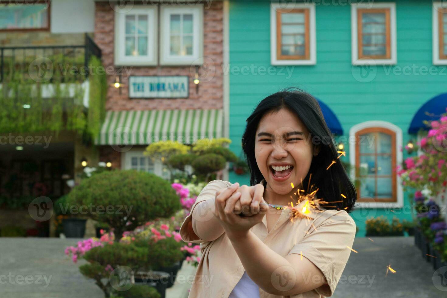 new year eve celebration concept. attractive asian young woman holding sparkler with laughing happy in outdoor garden of vintage house yard photo