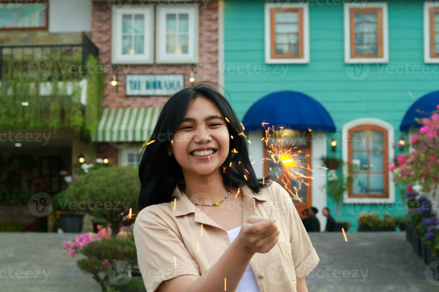 portrait of beautiful happy young asian woman holding sparklers fireworks to celebrate new year eve with garden party standing in outdoor vintage house yard photo