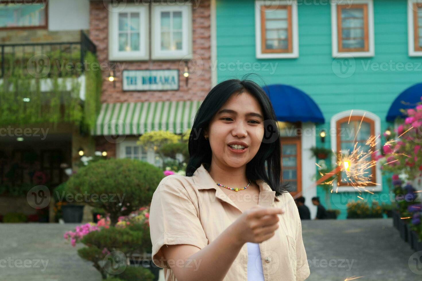 portrait of beautiful happy young asian woman holding sparklers fireworks to celebrate new year eve with garden party standing in outdoor vintage house yard photo