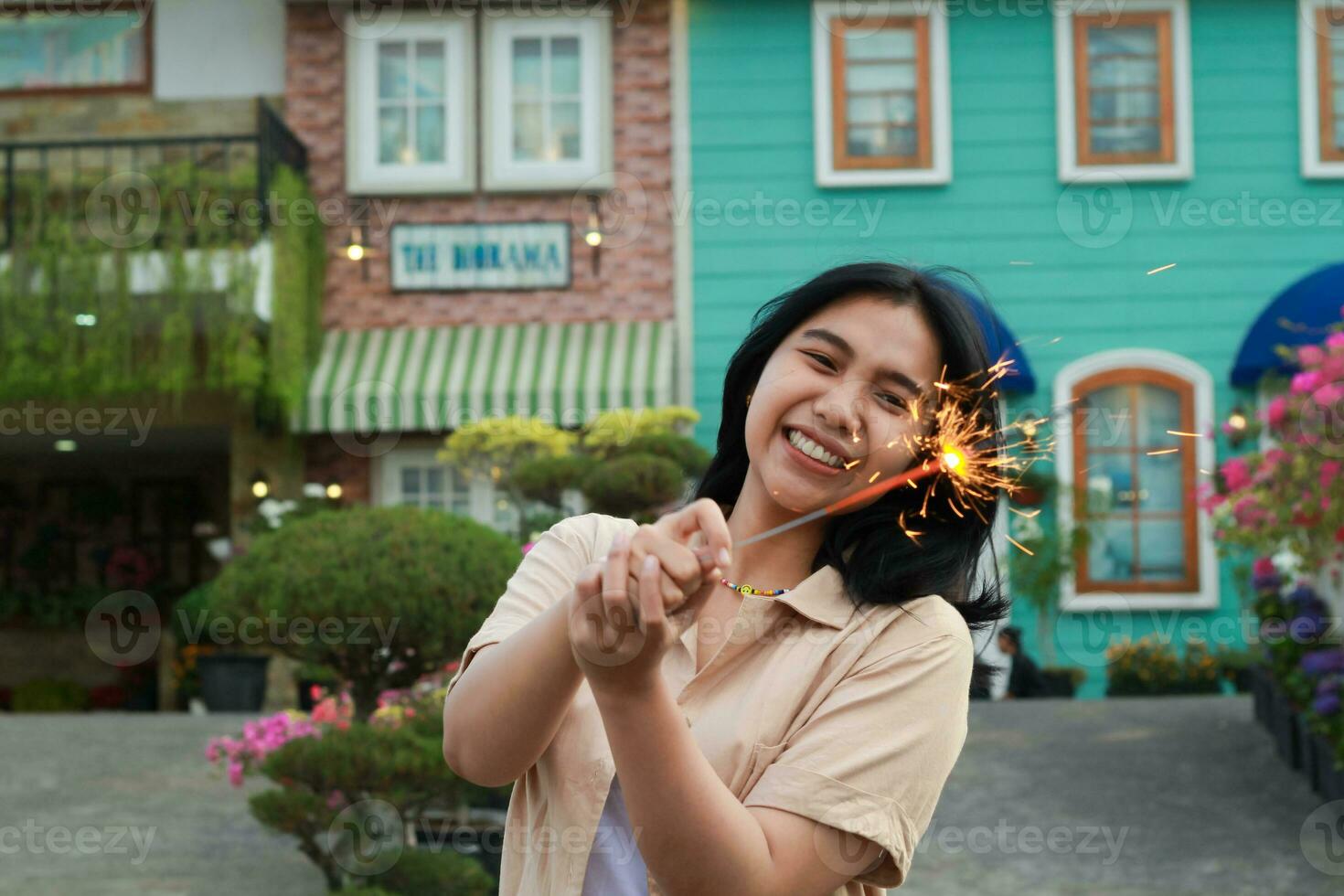 new year eve celebration concept. attractive asian young woman holding sparkler with laughing happy in outdoor garden of vintage house yard photo