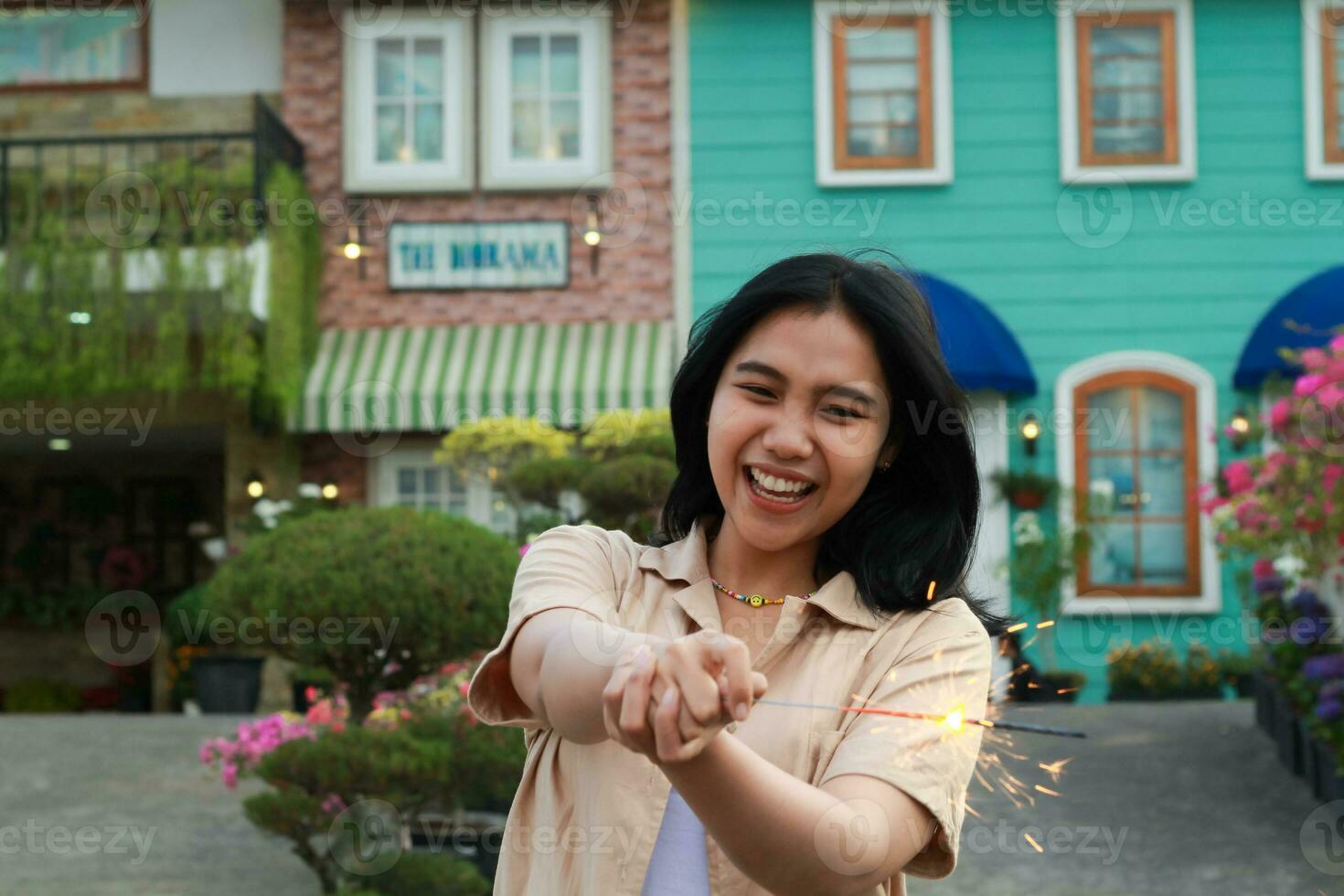 new year eve celebration concept. attractive asian young woman holding sparkler with laughing happy in outdoor garden of vintage house yard photo