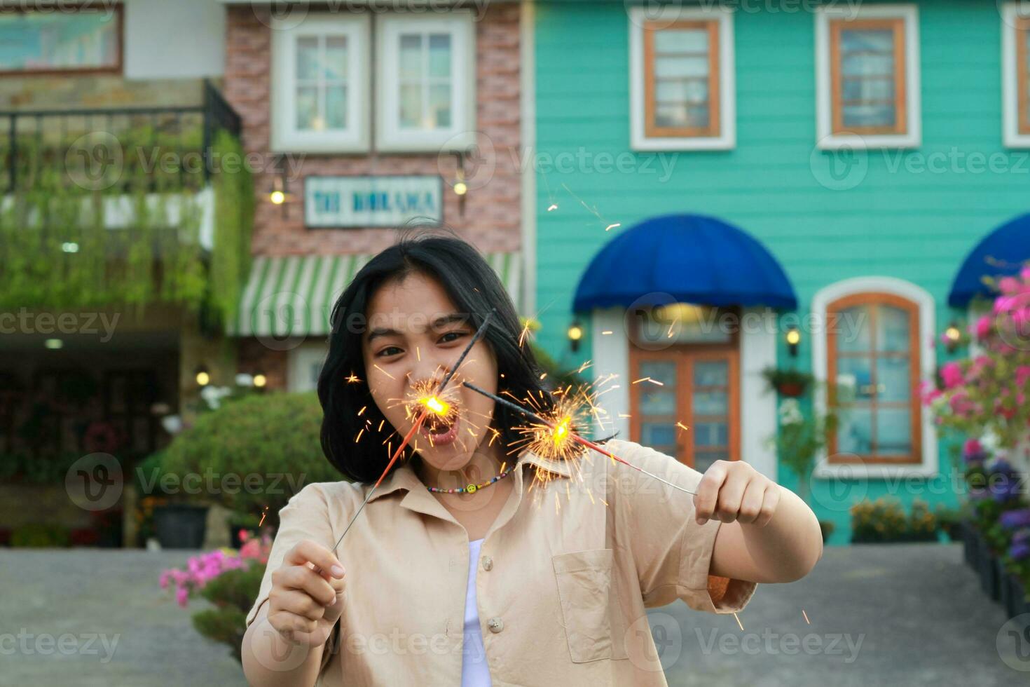 alegre joven asiático mujer participación bengala a celebrar nuevo año víspera con jardín fiesta en pie terminado vistoso Clásico casa yarda foto