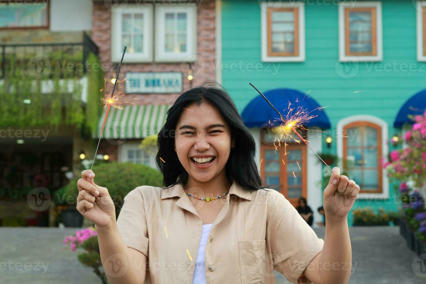 alegre joven asiático mujer participación bengala a celebrar nuevo año víspera con jardín fiesta en pie terminado vistoso Clásico casa yarda foto