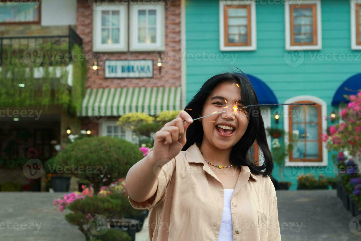 happy young asian woman holding sparkler enjoy new year eve celebration in outdoor garden of colorful vintage house in evening photo